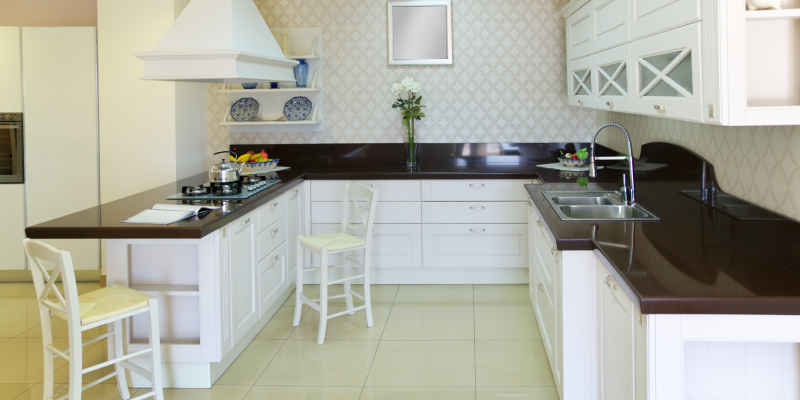 Modern kitchen with white cabinets, a brown countertop, white chairs, and modern appliances in a cozy setting.